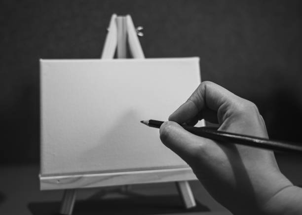 istock Hand with pencil on painting easel; Black and white style 1272506479