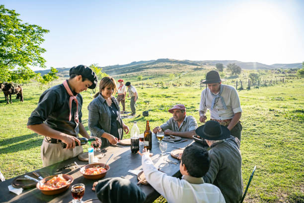 Argentine gaucho family enjoying outdoor midday meal Wide angle view of relaxed gaucho family enjoying food and drink outdoors for midday meal with sun-filled pampas in background. argentinian culture stock pictures, royalty-free photos & images