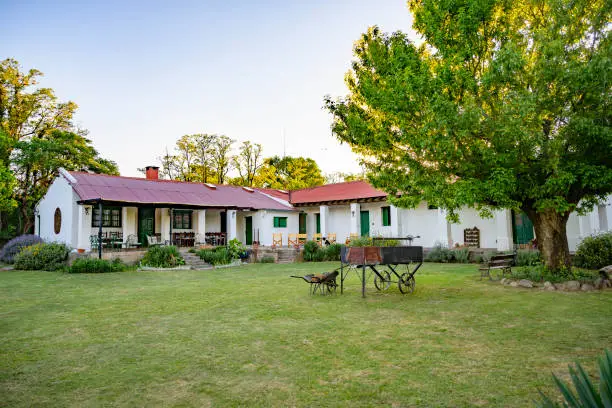 Close-up of Argentine estancia guesthouse with lawn, shade tree, and grill located in Sierras Chicas hills near Cordoba.
