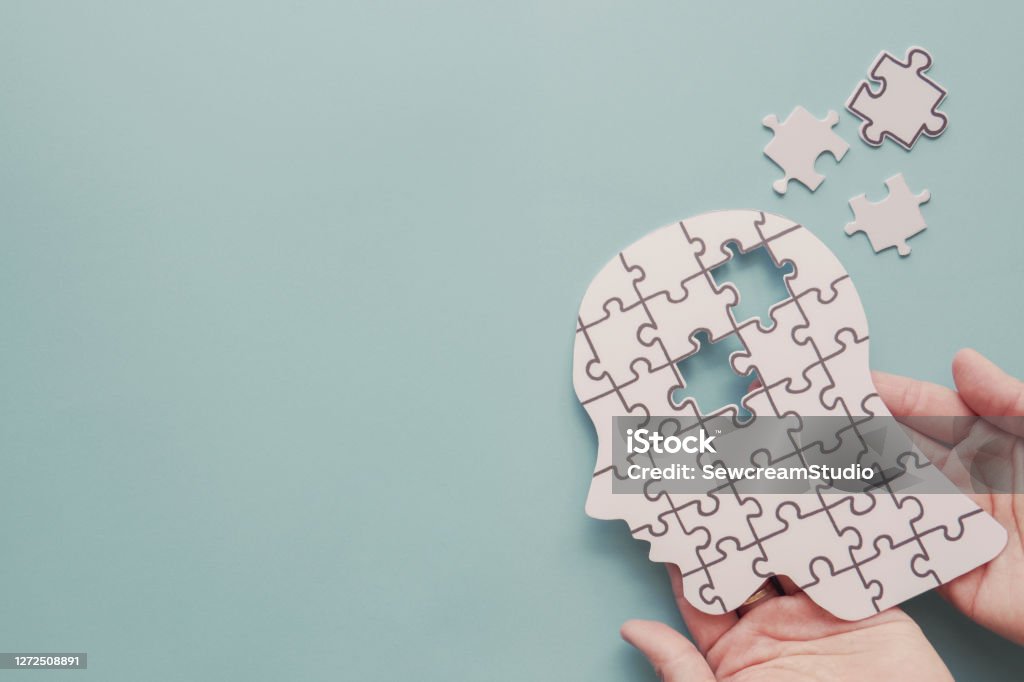Hands holding brain with puzzle paper cutout, autism, Epilepsy and alzheimer awareness, seizure disorder, world mental health day concept Mental Health Stock Photo
