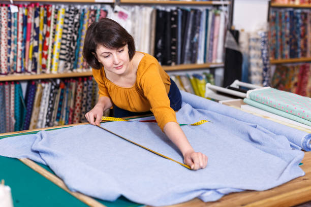 istock Saleswoman measuring cloth for cutting 1272509702