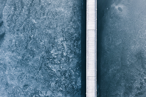 Aerial (drone) view on a bridge over the frozen lake.