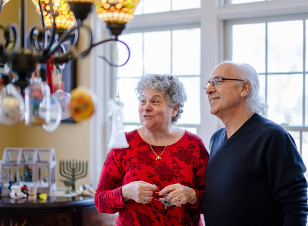 크리스마스와 하누카 모두 겨울 휴가를 위해 집을 꾸미는 선임 부부. - hanukkah menorah candle judaism 뉴스 사진 이미지