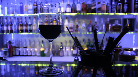 A glass of red wine placed on the counter bar at night