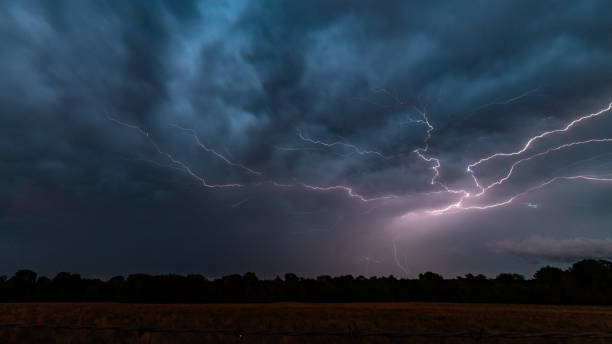 Lightning Over a Field A bolt of lightning on the backside of a thunderstorm in College Station, Texas. thunderstorm stock pictures, royalty-free photos & images