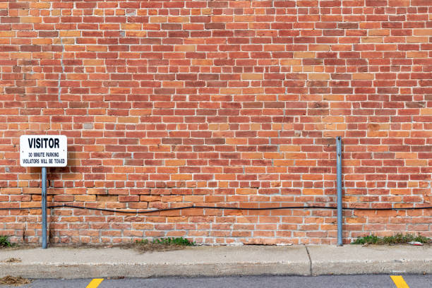 istock Antique reddish brown brick wall with Visitor Parking sign 1272523555