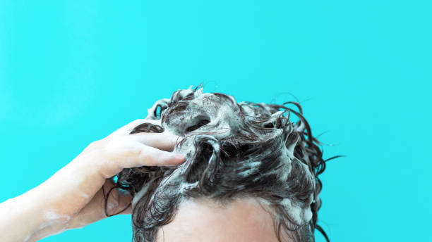 istock A girl washes her hair with shampoo on blue background, front view 1272525693