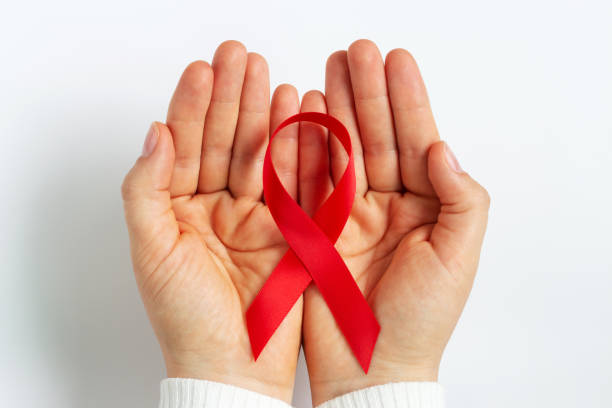 Female hands hold a red ribbon on white background top view. Female hands hold a red ribbon on a white background top view. HIV Stigma stock pictures, royalty-free photos & images