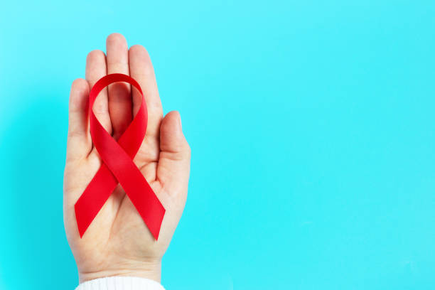istock A woman's hand holds red ribbon on blue background 1272526386
