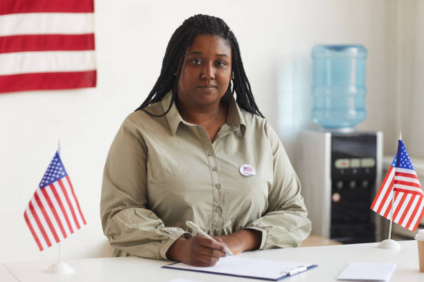 African-American Woman at Voting Station Portrait of smiling African-American woman working at at polling station on election day and registering voters, copy space voter registration photos stock pictures, royalty-free photos & images