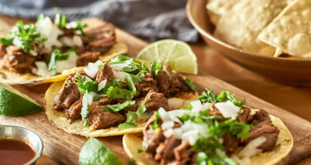 three carne asada mexican street tacos in corn tortilla with lime close up