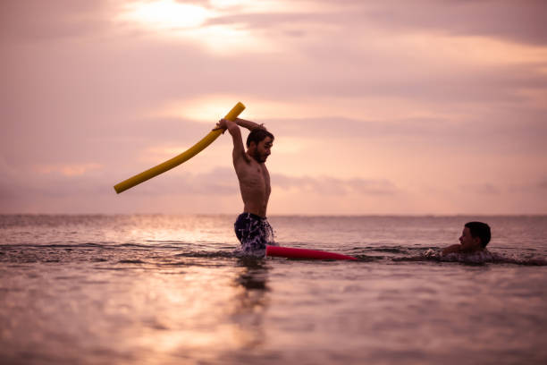 istock Fighting with pool noodles on the beach 1272533577