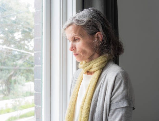 istock Sad middle aged woman next to window 1272535420