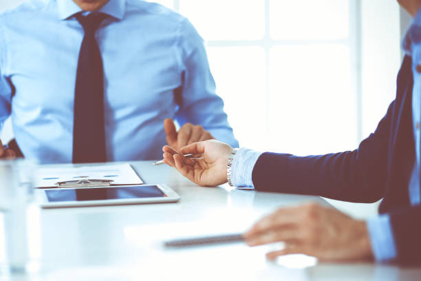 istock Two unknown businessmen or partners using tablet pc and discussing questions at meeting in modern office, close-up of hands. Group of managers at negotiation or brainstorm. Teamwork, partnership and business concept 1272541686