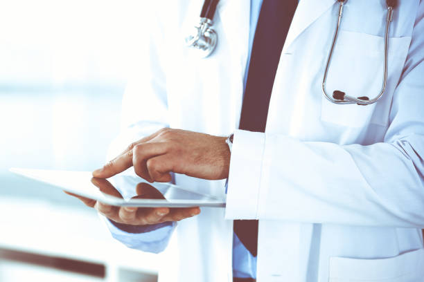 istock Doctor man using tablet computer for network research or virtual disease treatment, hands close-up. Perfect medical service in clinic. Modern medicine, medic data and healthcare concepts. Toned picture 1272541725