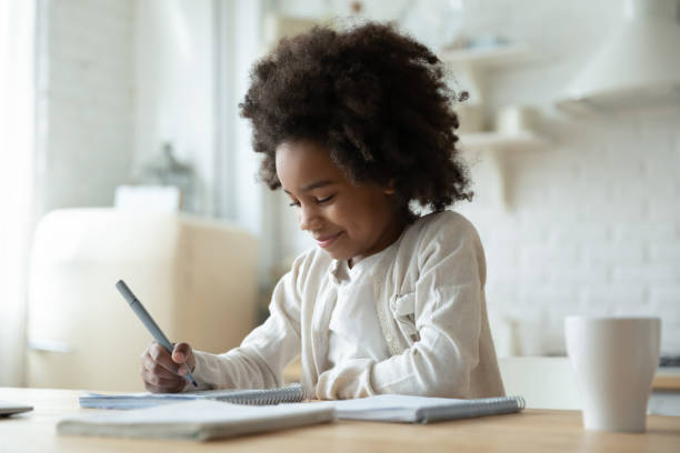 african ethnicity little girl preparing interesting homework. - child thinking writing little girls imagens e fotografias de stock