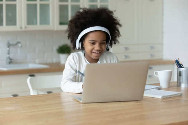 istock African ethnicity small girl wearing headphones, looking at computer screen. 1272542101