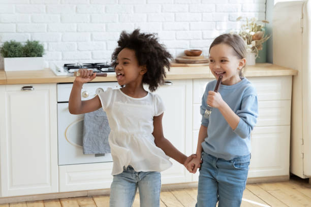 petits enfants d’âge préscolaire de course mélangée appréciant des chansons chantantes dans la cuisine. - différence dâge photos et images de collection