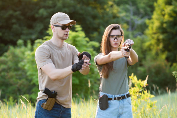 A girl learns to shoot a pistol with an instructor at the training ground
