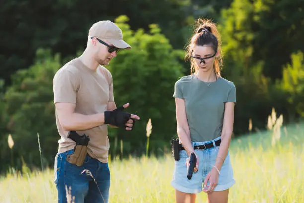 Photo of A girl learns to shoot a pistol with an instructor at the training ground