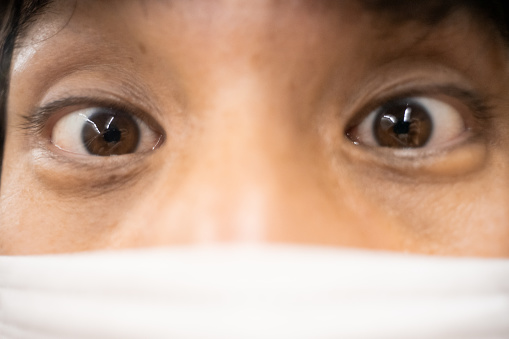An extreme close-up photo of an Asian man wearing a mask and his eyes.