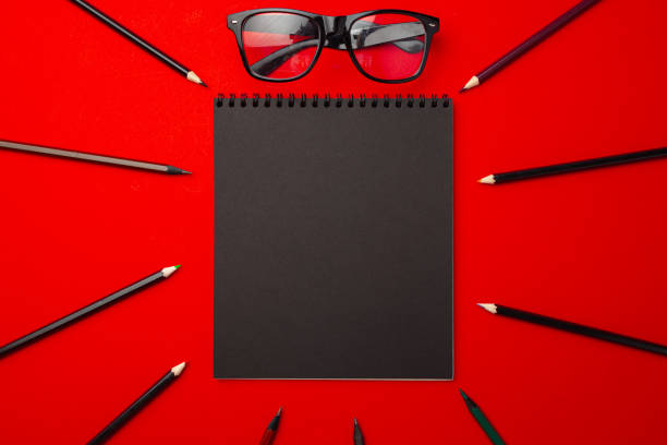istock Black pencils and glasses on red background top view 1272553172
