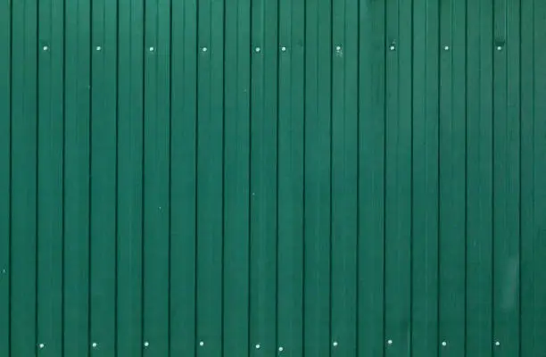 Photo of Background of painted corrugated tin iron with galvanized screw heads and vertical orientation