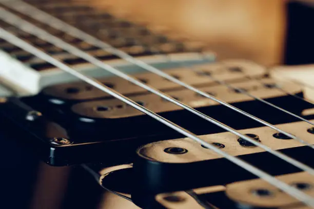 Close up photo of electric guitar fingerboard on dark background