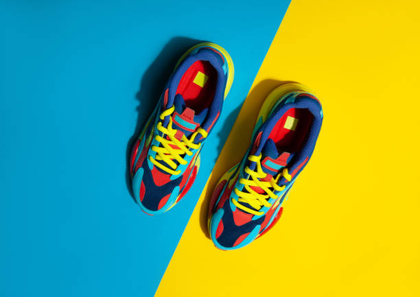 istock Multicolor sport shoes on yellow background with shadows 1272557385