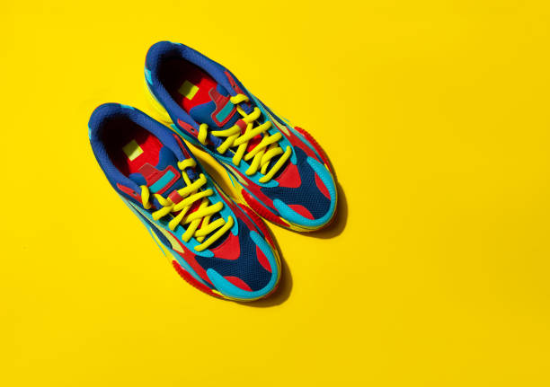 istock Multicolor sport shoes on yellow background with shadows 1272557389