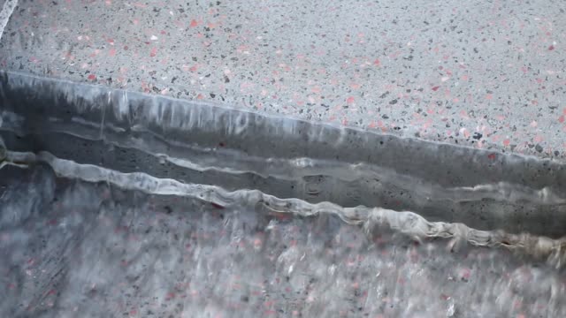 Clear drinking spring water running, grey granite