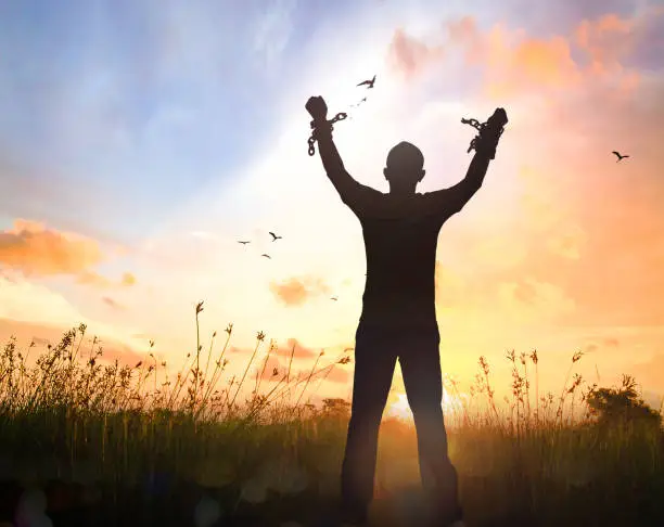 Silhouette human hand broken chains against twilight sky autumn sunset background