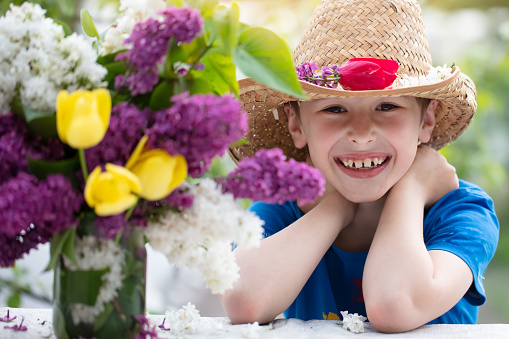 Cheerful child in a straw hat with a lilac. Happy boy on summer vacation.