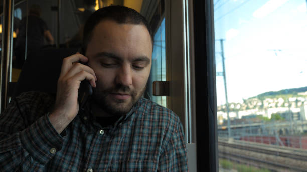 istock Handsome man talking on mobile phone in train 1272563730