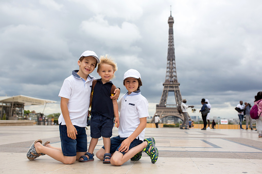 Happy siblings, boys, visiting Paris during the summer, standing in front of the Eiffel tower