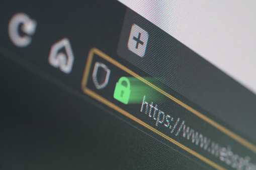 Dark web browser close-up on LCD screen with shallow focus, light shining through https padlock. Internet security, SSL certificate, cybersecurity, search engine and web browser concepts