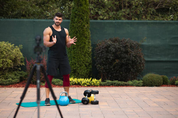 istock Male athlete doing exercise in backyard and filming vlog. 1272566472