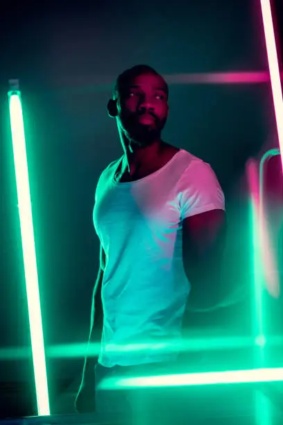 Photo of Cinematic portrait of handsome young man in neon lighted room, stylish musician