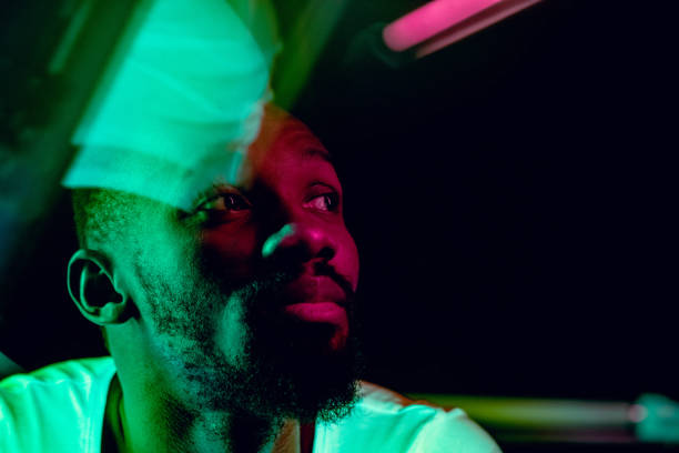 cinematic portrait of handsome young man in neon lighted room, stylish musician - serious african ethnicity mid adult bright imagens e fotografias de stock