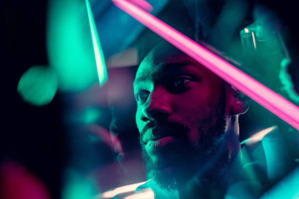 cinematic portrait of handsome young man in neon lighted room, stylish musician - serious african ethnicity mid adult bright imagens e fotografias de stock