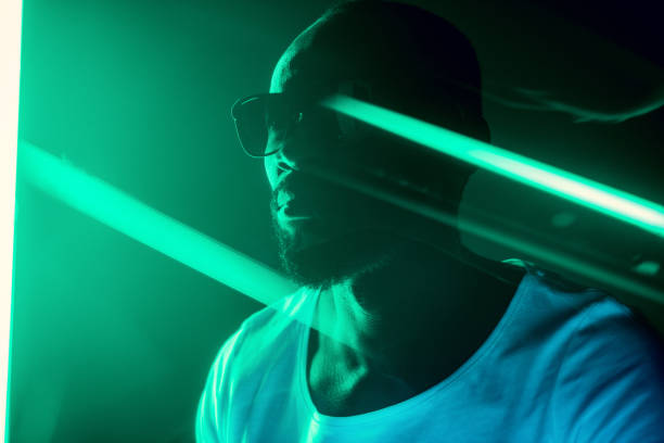 cinematic portrait of handsome young man in neon lighted room, stylish musician - serious african ethnicity mid adult bright imagens e fotografias de stock