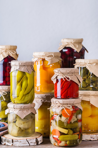 Preserved and fermented food. Assortment of homemade jars with variety of pickled and marinated vegetables, fruit compote on a wooden table. Housekeeping, home economics, harvest preservation
