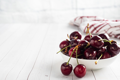 Ripe juicy cherry berries on a plate. White background. Copy space