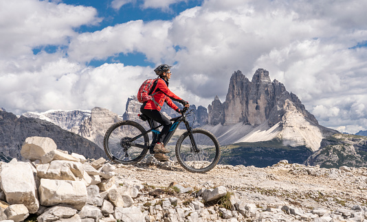 nice senior woman, riding her electric mountain bike below the famous Three peak of Lavaredo in the Sexten Dolomites in South tirol, Italy