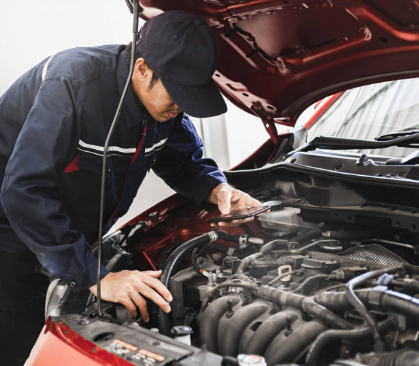 istock Asian Man mechanic inspection Shine a torch car engine checking bug in engine from application smartphone.Red car for service maintenance insurance with car engine.for transport automobile automotive 1272571759