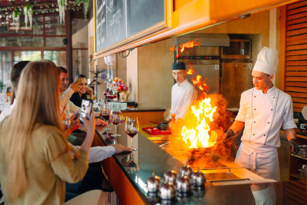 The chef prepares food in front of the visitors in the restaurant stock photo