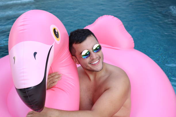 istock Ethnic man in large inflatable pink flamingo 1272575004