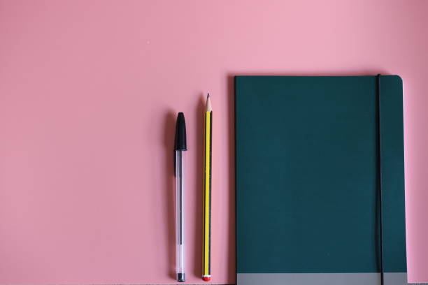 istock Back to school. Tidy desk for study with a pale pink background and a notebook with pencil and pen. Grey school bag. Masks to protect the study against coronavirus 1272576039
