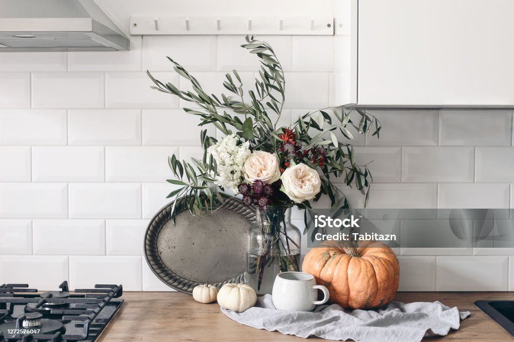 Autumn still life composition in rustic eclectic kitchen interior. Cup of coffee, vintage silver tray and floral bouquet. Wooden table background with pumkins. Thanksgiving, Halloween concept. Autumn still life composition in rustic eclectic kitchen interior. Cup of coffee, vintage silver tray and floral bouquet. Wooden table background with pumkins, thanksgiving, Halloween concept. Autumn Stock Photo