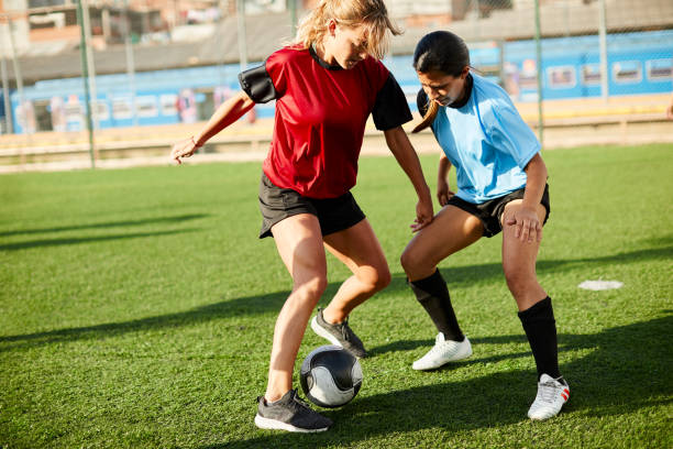 istock Female soccer player dribbling an opponent defender. 1272577201